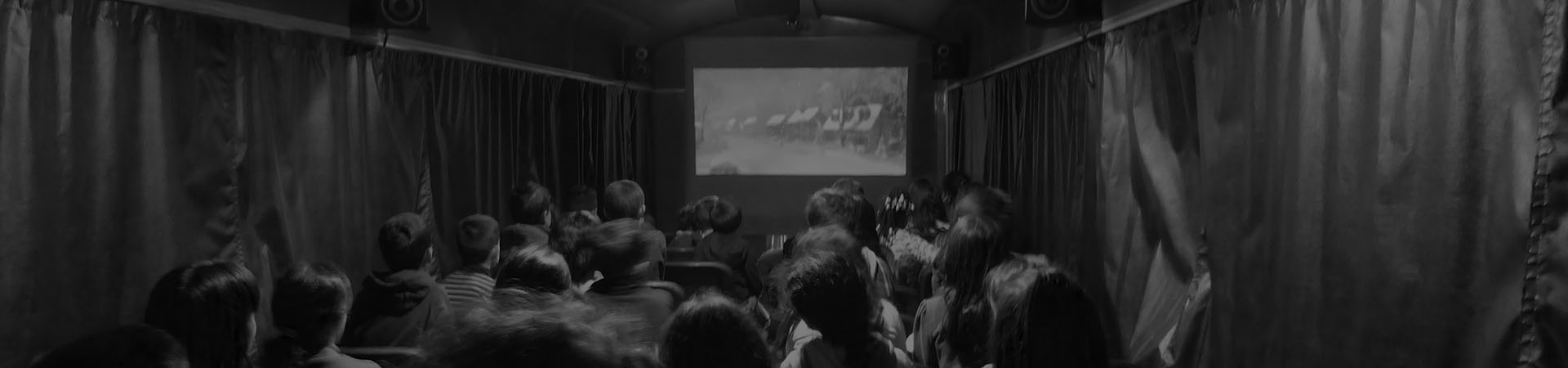 Fotografia de um grupo de crianças a ver um filme na carruagem auditório durante uma festa de aniversário